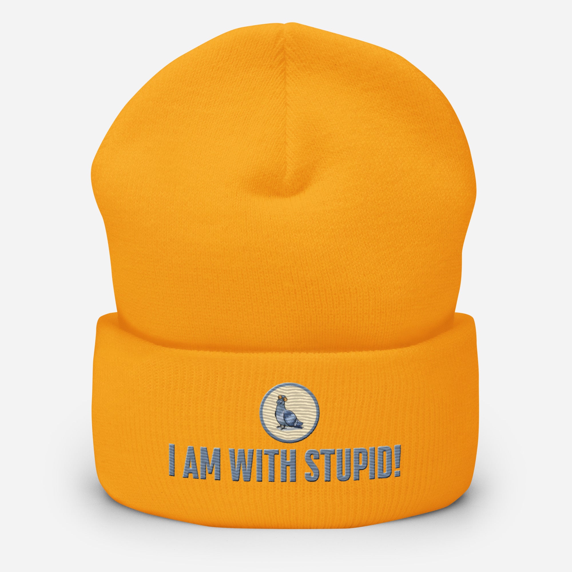 Eine gold-gelbe Cuffed Beanie mit aufgesticktem Patch als Taube mit einem runden beige-grauen Rahmen auf der Vorderseite. Darunter ein Schriftzug mit Grossgeschriebenen Buchstaben "I Am with Stupid!" Designed, by Just a Girl.