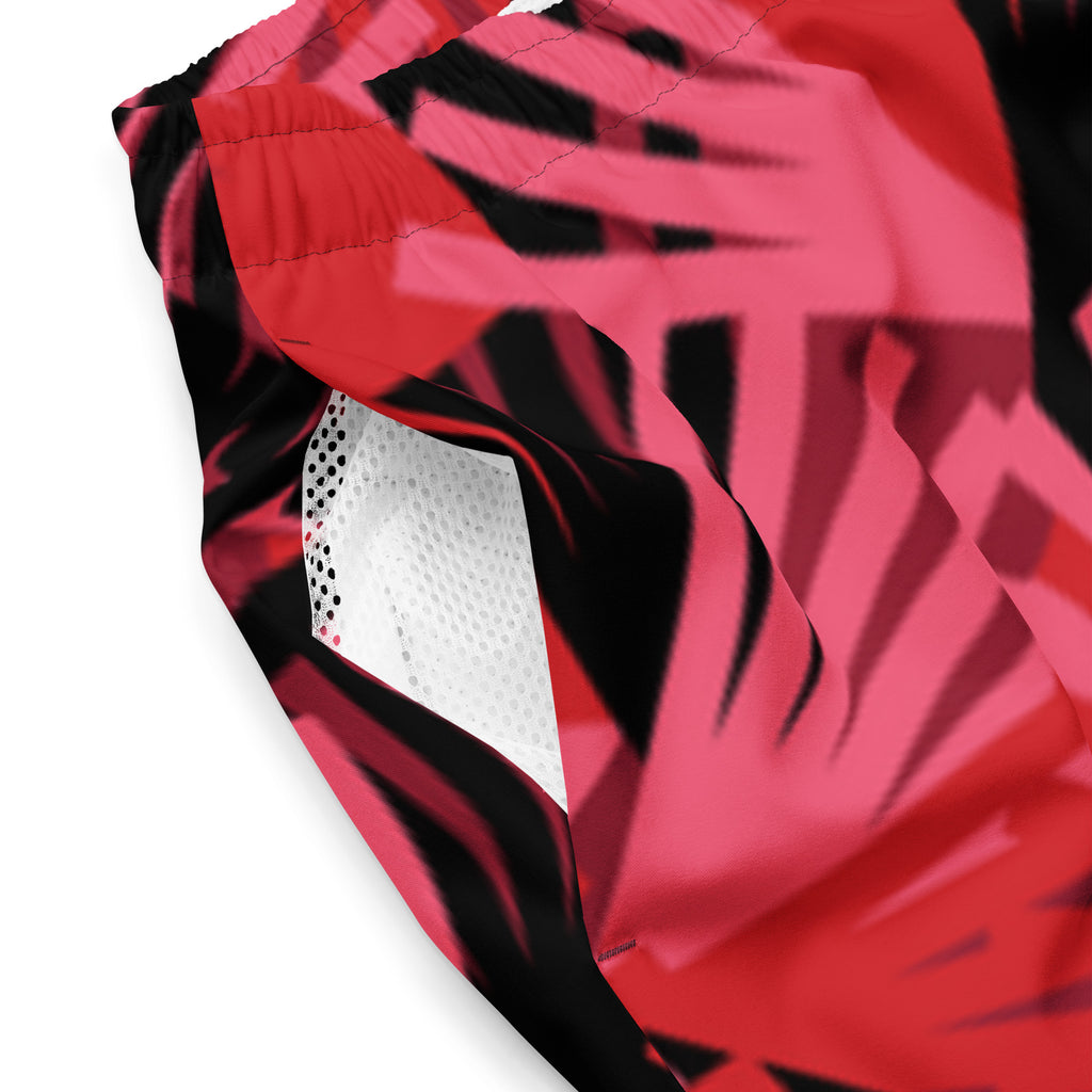 Eine Badeshorts mit einem Muster aus violetten Palmen und anderen stilisierten Pflanzen auf einem hellbeigen Hintergrund mit feinen, horizontalen Linien. Der Bund der Shorts ist elastisch.