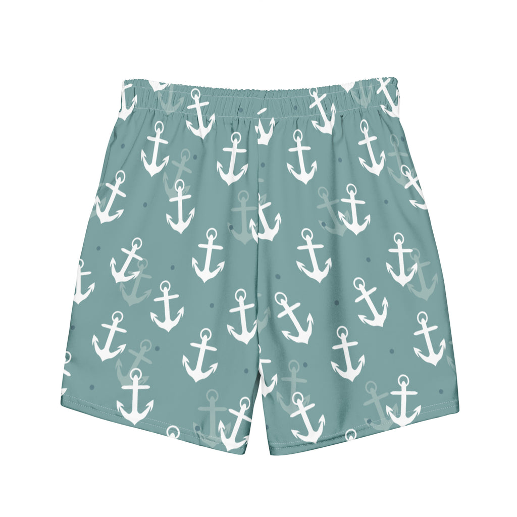 Eine Badeshorts in einem gedeckten Türkis- oder Blauton mit einem wiederkehrenden Muster aus weißen und hellgrauen Ankern und kleinen blauen Punkten. Der Bund ist elastisch und farblich passend.