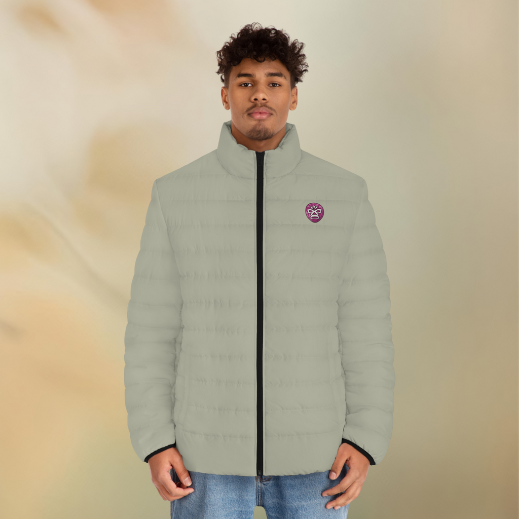 Ein weibliches Model zeigt tragend die Herren-Pufferjacke Vorderansicht in einem Aschgrauen Farbton. Die Jacke ist horizontal gesteppt, hat eine glatte Oberfläche, einen hohen Stehkragen und einen durchgehenden Reißverschluss der Schwarz ist . Auf der linken Brusthöhe ist ein Emblem im Maori Stil. Designed, by Just a Girl