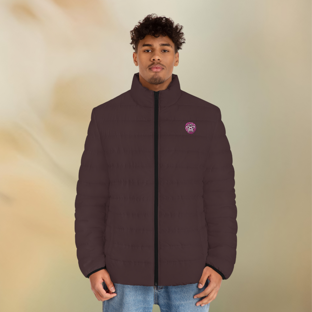 Ein männliches Model zeigt tragend die Herren-Pufferjacke in der Vorderansicht in einem Schokoladenbraunen Farbton. Die Jacke ist horizontal gesteppt, hat eine glatte Oberfläche, einen hohen Stehkragen und einen durchgehenden Reißverschluss. Die Jacke hat auf der linken Brust ein Maori Emblem. Designed, by Just a Girl

