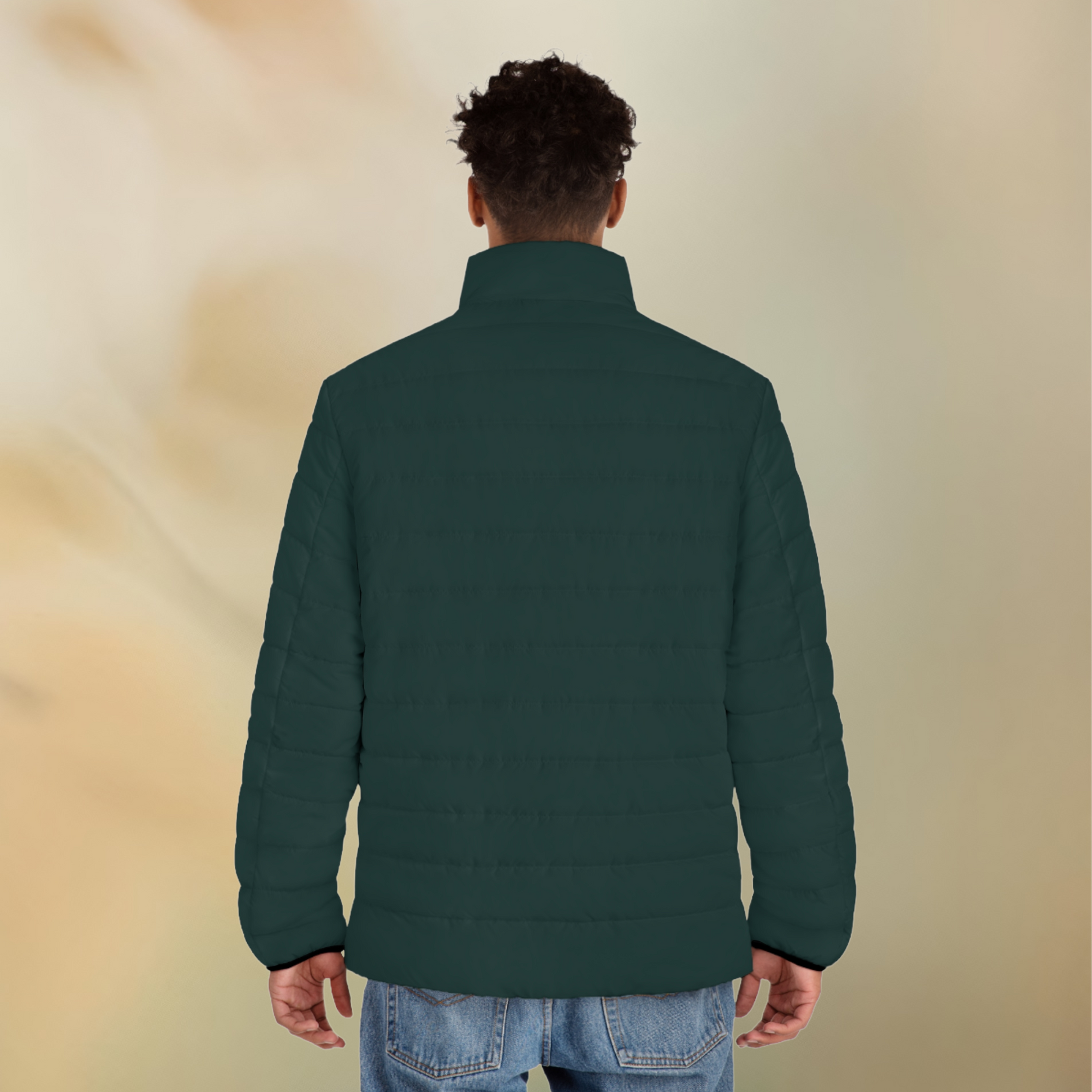 Ein männliches Model zeigt tragend mit der Rückenansicht die Herren-Pufferjacke  in einem Tiefen Tafel Farbton. Die Jacke ist horizontal gesteppt, hat eine glatte Oberfläche sowie einen hohen Stehkragen.  Designed, by Just a Girl