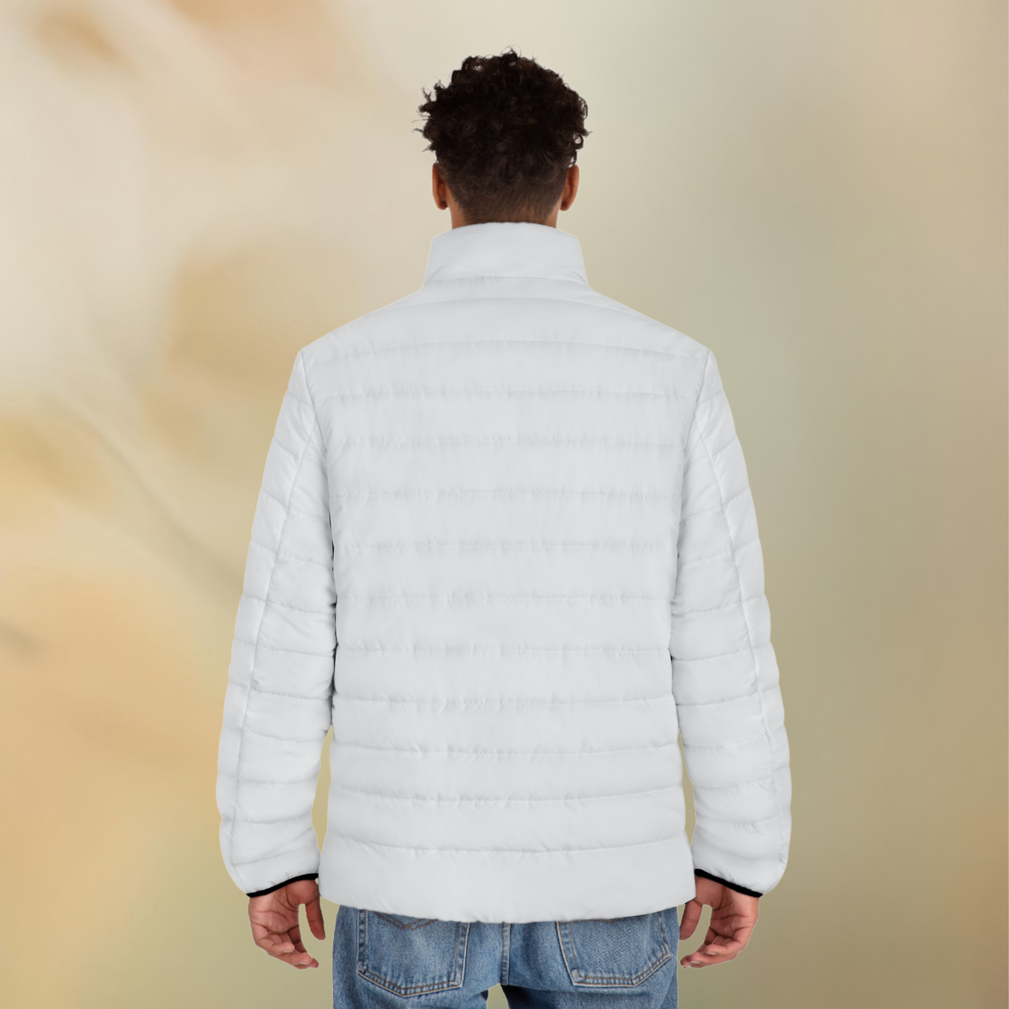 Ein männliches Model zeigt tragend mit der Rückenansicht die Herren-Pufferjacke in einem Elfenbein Farbton. Die Jacke ist horizontal gesteppt, hat eine glatte Oberfläche sowie einen hohen Stehkragen. Designed, by Just a Girl

