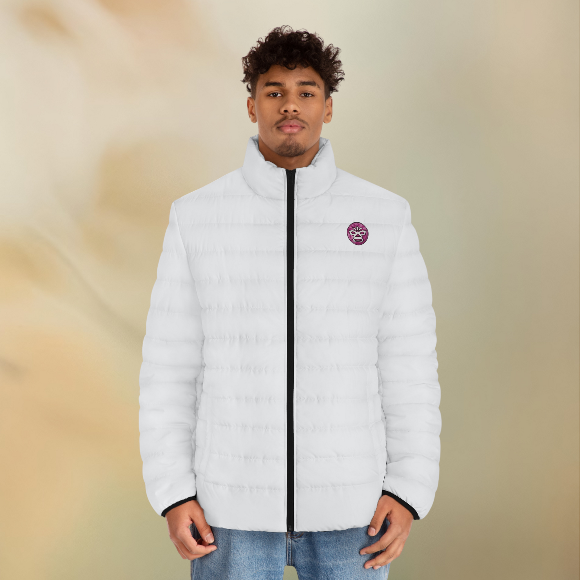 Ein männliches Model zeigt tragend in der Vorderansicht die Herren-Pufferjacke in einem Elfenbein Farbton. Die Jacke ist horizontal gesteppt, hat eine glatte Oberfläche, einen hohen Stehkragen und einen durchgehenden Reißverschluss der schwarz ist. Die Jacke hat auf der linken Brust ein Emblem im Maori Stil. Designed, by Just a Girl

