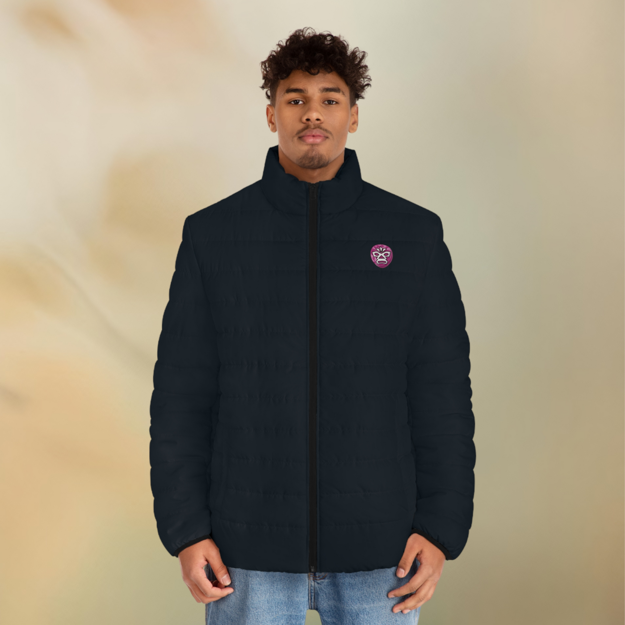 Ein männliches Model zeigt tragend die Herren-Pufferjacke in einem natürlichen schwarzen Farbton. Die Jacke ist horizontal gesteppt, hat eine glatte Oberfläche, einen hohen Stehkragen und einen durchgehenden Reißverschluss der Schwarz ist . Auf der linken Brusthöhe ist ein Emblem im Maori Stil. Designed, by Just a Girl

