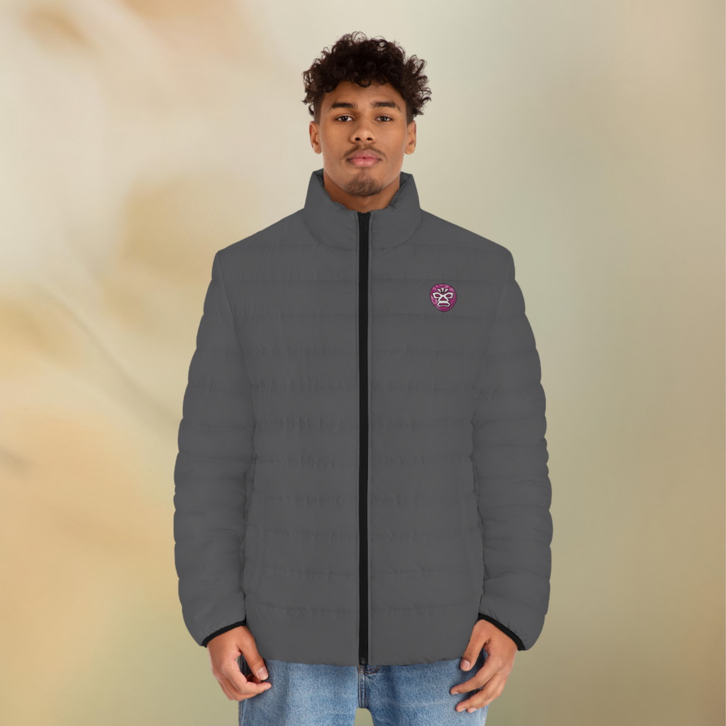 Ein männliches Model zeigt tragend die  Herren-Pufferjacke in einem Grey Stone Farbton. Die Jacke ist horizontal gesteppt, hat eine glatte Oberfläche, einen hohen Stehkragen und einen durchgehenden Reißverschluss. Auf der lingen Brusthöhe befindet sich ein Maori Emblem. Designed, by Just a Girl

