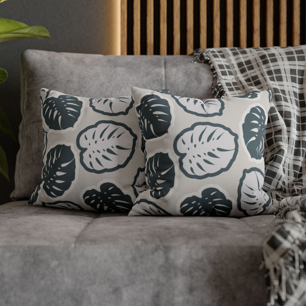 Ein paar Monstera Kissen dekoriert auf einem grauen Sofa. 