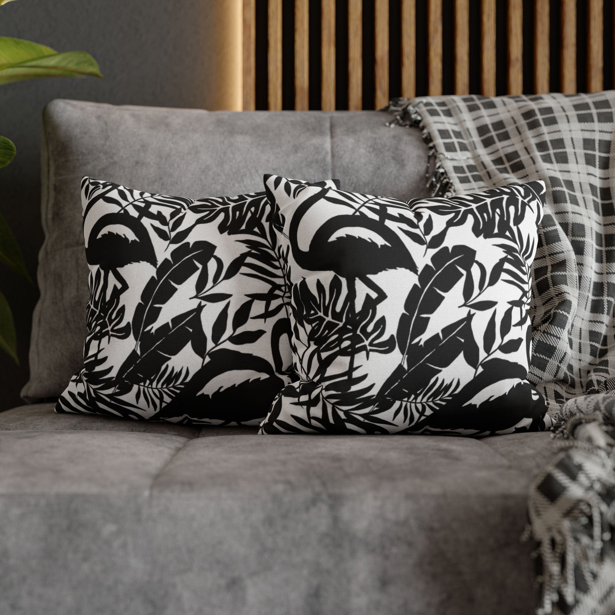 Ein paar Flamingo Jungle Kissen dekoriert auf einem grauen Sofa. 
