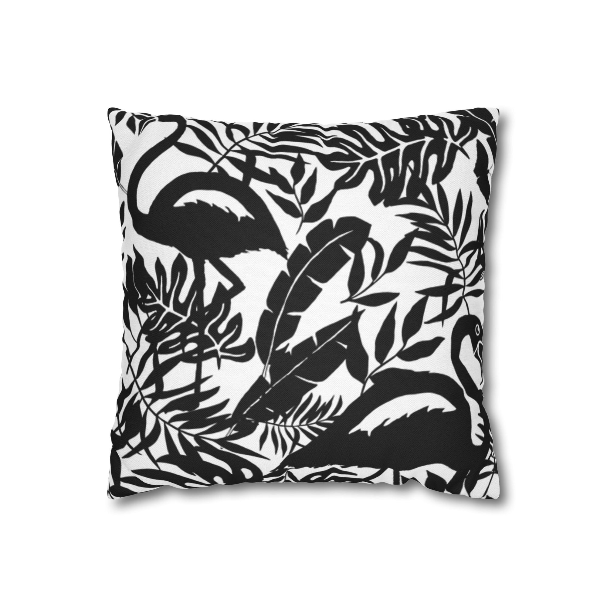 Ein quadratisches Kissen, bedruckt mit einem Schwarz-Weiß-Muster aus Flamingos und verschiedenen tropischen Blättern. Die Muster sind als dunkle Silhouetten vor einem weißen Hintergrund dargestellt. Das Kissen wird von oben gesehen und hat einen Schattenwurf, der es auf einem weißen Hintergrund schweben lässt.