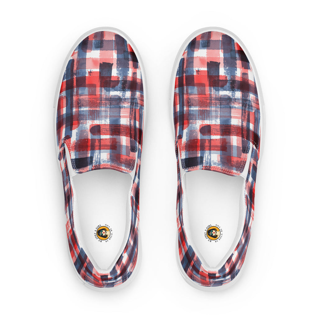 Ein Paar weißer Slip-On Canvas Schuhe mit einem abstrakten, gitterartigen Muster aus breiten, transparenten Pinselstrichen in Rot, Dunkelblau und Hellblau, die sich überlappen und ein kariertes Aussehen erzeugen. Die Sohle ist weiß. Die Schuhe sind leicht nach links gedreht, sodass die Vorderseite beider Schuhe sichtbar ist.