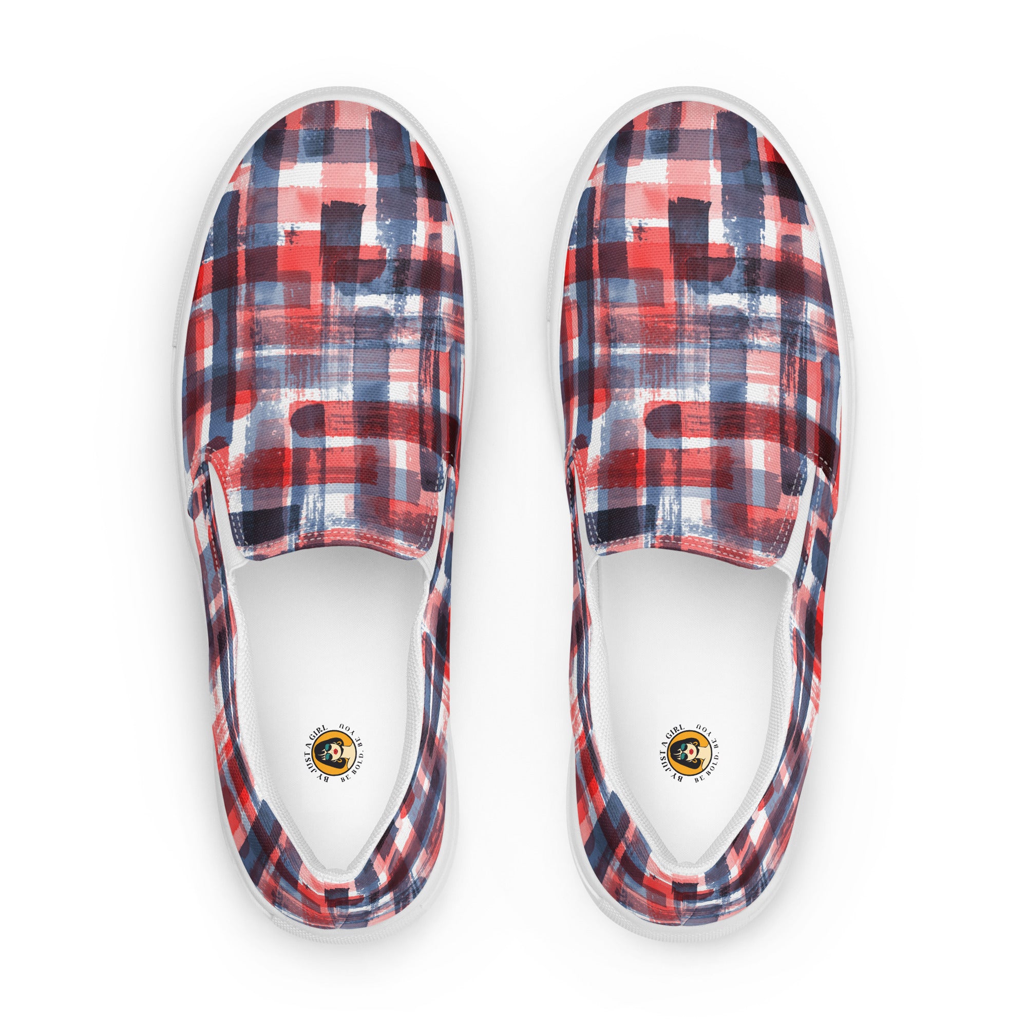 Ein Paar weißer Slip-On Canvas Schuhe mit einem abstrakten, gitterartigen Muster aus breiten, transparenten Pinselstrichen in Rot, Dunkelblau und Hellblau, die sich überlappen und ein kariertes Aussehen erzeugen. Die Sohle ist weiß. Die Schuhe sind leicht nach links gedreht, sodass die Vorderseite beider Schuhe sichtbar ist.