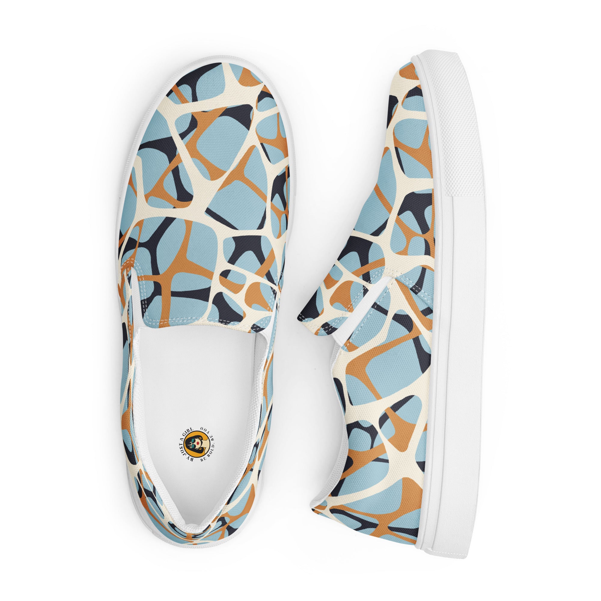 Ein Paar cremefarbener Slip-On Canvas Schuhe mit einem organischen, unregelmäßigen Muster in Hellblau, Orange und Dunkelgrau. Die Sohle ist weiß. Die Schuhe sind leicht nach links gedreht, sodass die Vorderseite beider Schuhe sichtbar ist.