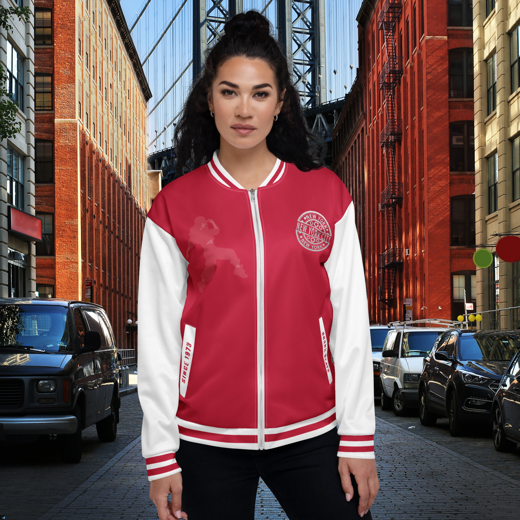 Das Model zeigt die Rot-weiße "Bronx Beats" Jacke since 1973 und zeigt sich von vorne. Auf der linken Brunst befindet sich ein Rundes Emblem mit New York City Kreis und Sternen. Auf der rechten Seite ist ein Hip Hop Girl abgebildet doch sehr dezente Ansicht wurde sehr transparent gehalten. By Just a Girl.