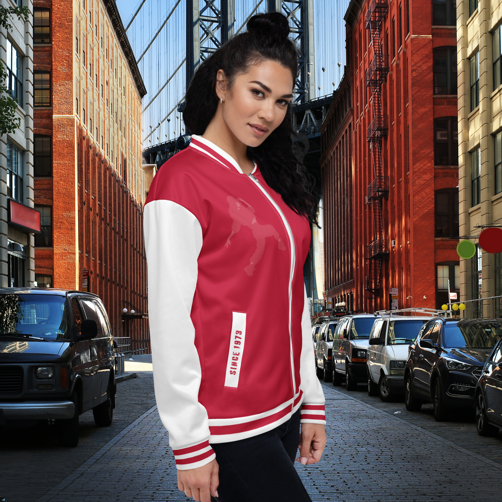 Seitliche Ansicht der Bronx Beats Jacke since 1973 getragen von einem weiblichen Model. Die Jacke ist Rot´-weiß gehalten die Ärmel sind weiß und die Bündchen haben 2 rote Streifen sowie der Kragen und der Jackenbund unten. Die Taschenbündchen sind in weiß gehalten auf der einen Seite steht mit alter Fabrikschrift "Bronx Beats und auf der anderen Seite Since 1973" by Just a Girl.