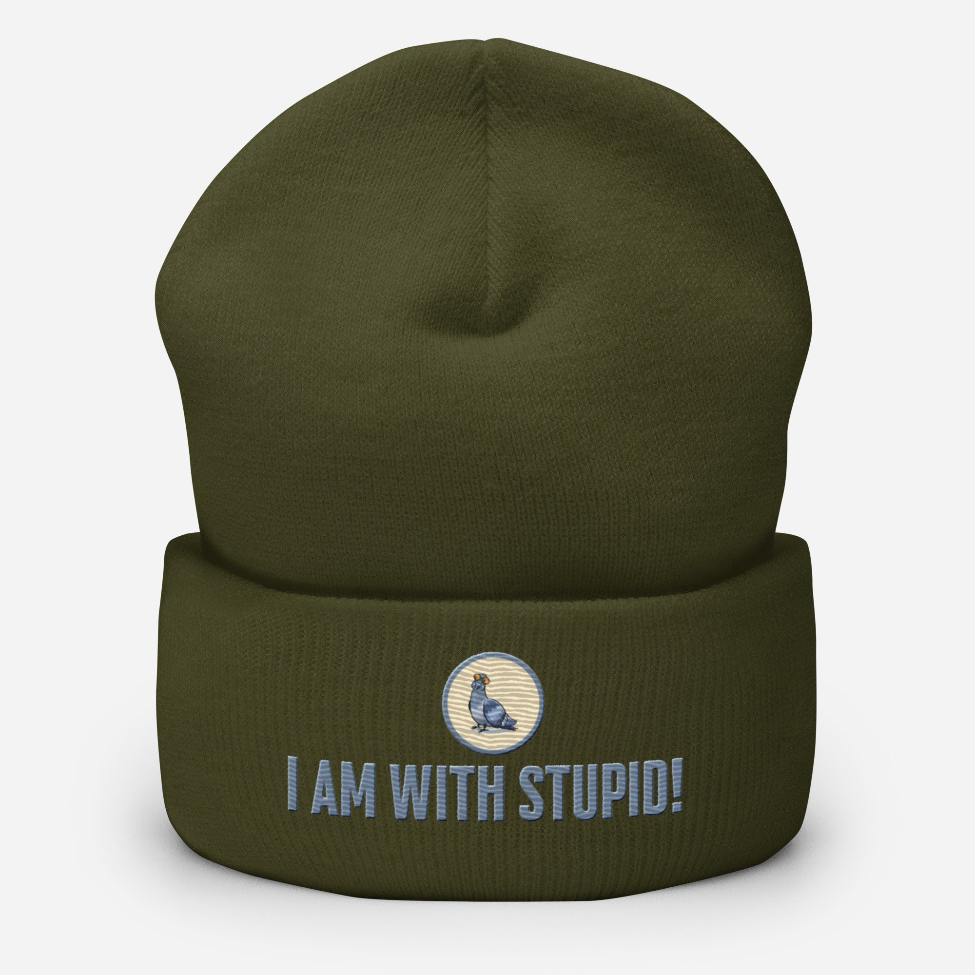 Eine Oliv farbene Cuffed Beanie mit aufgesticktem Patch als Taube mit einem runden beige-grauen Rahmen auf der Vorderseite. Darunter ein Schriftzug mit Grossgeschriebenen Buchstaben "I Am with Stupid!" Designed, by Just a Girl.