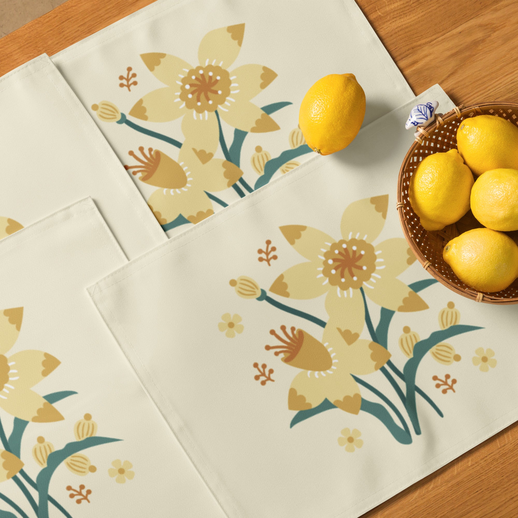 Set aus vier rechteckigen cremefarbenen Tischuntersetzern mit einer zentralen floralen Illustration von gelben Narzissen und kleinen orangen Blüten