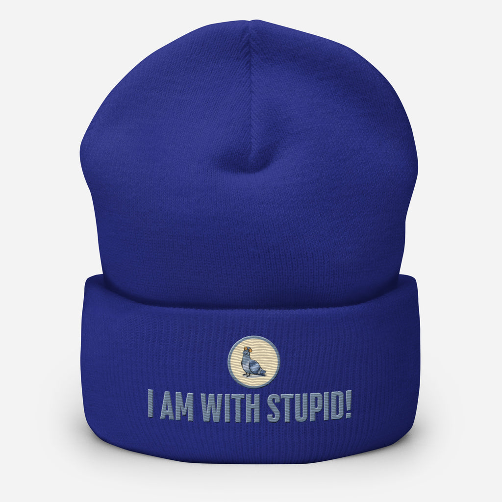 Eine Royal Blaue Cuffed Beanie mit aufgesticktem Patch als Taube mit einem runden beige-grauen Rahmen auf der Vorderseite. Darunter ein Schriftzug mit Grossgeschriebenen Buchstaben "I Am with Stupid!" Designed, by Just a Girl.