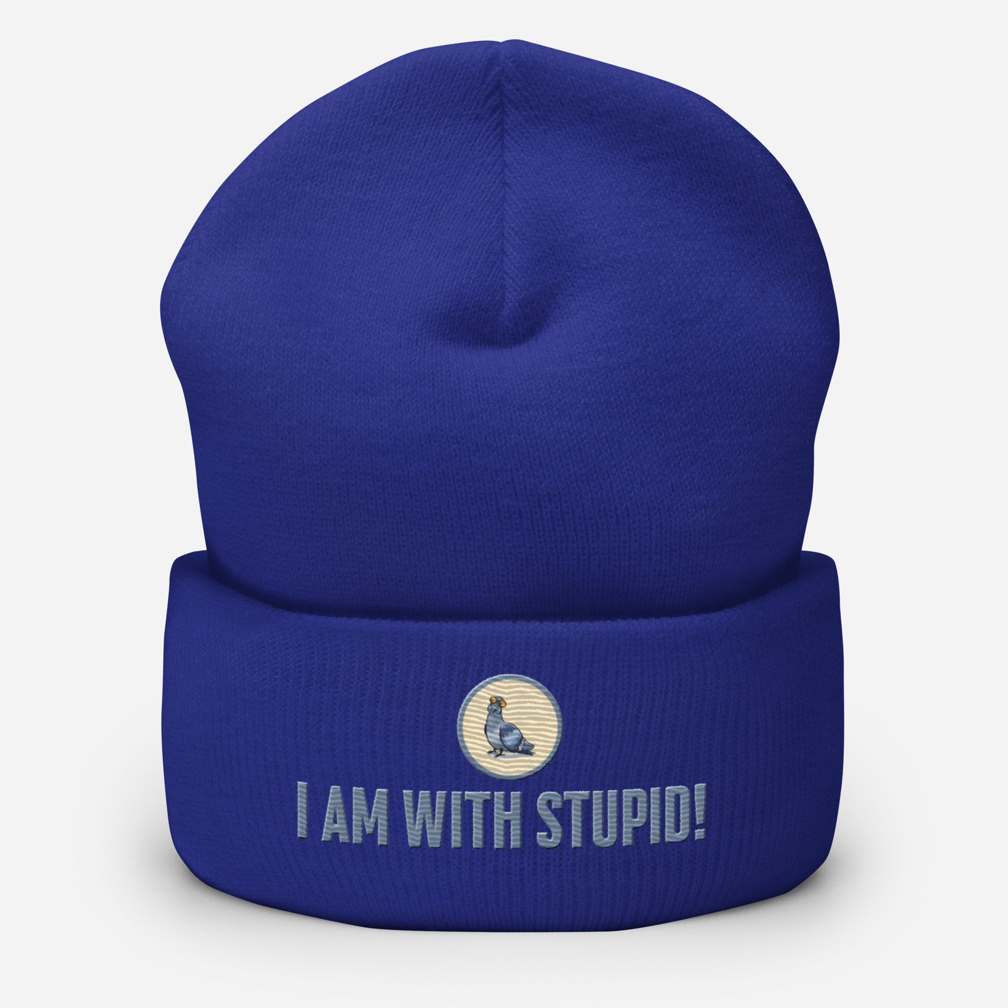 Eine Royal Blaue Cuffed Beanie mit aufgesticktem Patch als Taube mit einem runden beige-grauen Rahmen auf der Vorderseite. Darunter ein Schriftzug mit Grossgeschriebenen Buchstaben "I Am with Stupid!" Designed, by Just a Girl.
