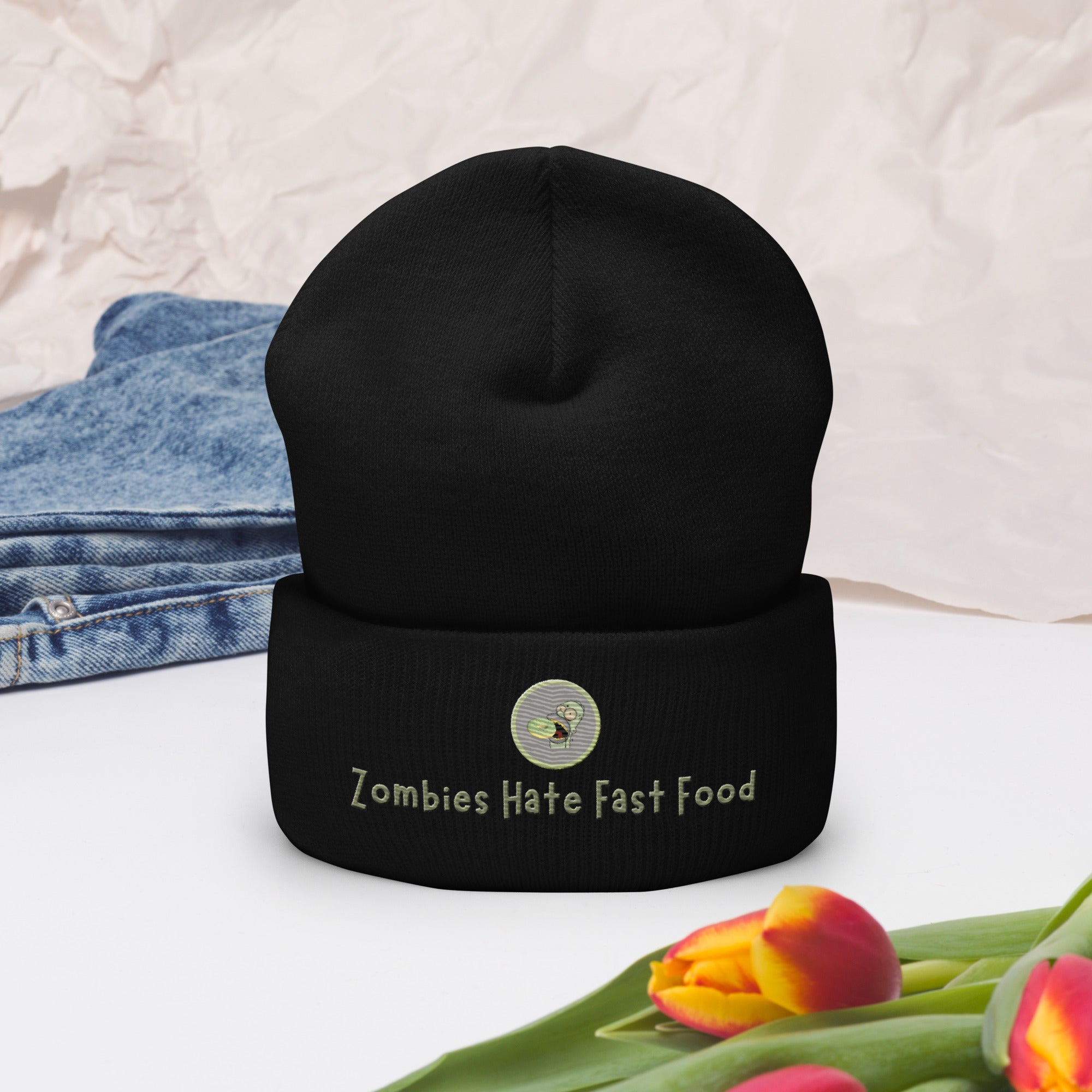 Ein schwarzes Cuffed Beanie mit aufgesticktem Patch von Homer und einem Donut mit einem grau-salbei farbenen Rahmen sowie einen Schriftzug darunter mit dem Satz "Zombies Hate Fast Food!" auf der Vorderseite. Dekoriert mit Jeans  und Blumen. Designed, by Just a Girl.