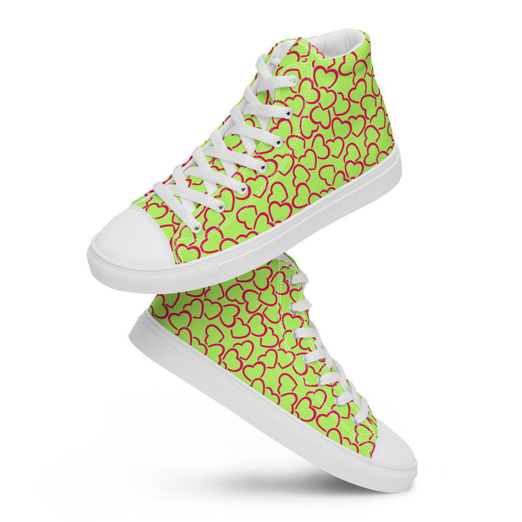 Ein Paar schwebende weiße High-Top-Sneaker mit einem durchgängigen Muster aus ineinandergreifenden, neonrosa umrandeten Herzen auf einem leuchtend lindgrünen Hintergrund. Die Schnürsenkel und Zehenkappen sind weiß. Designed, by Just a Girl.