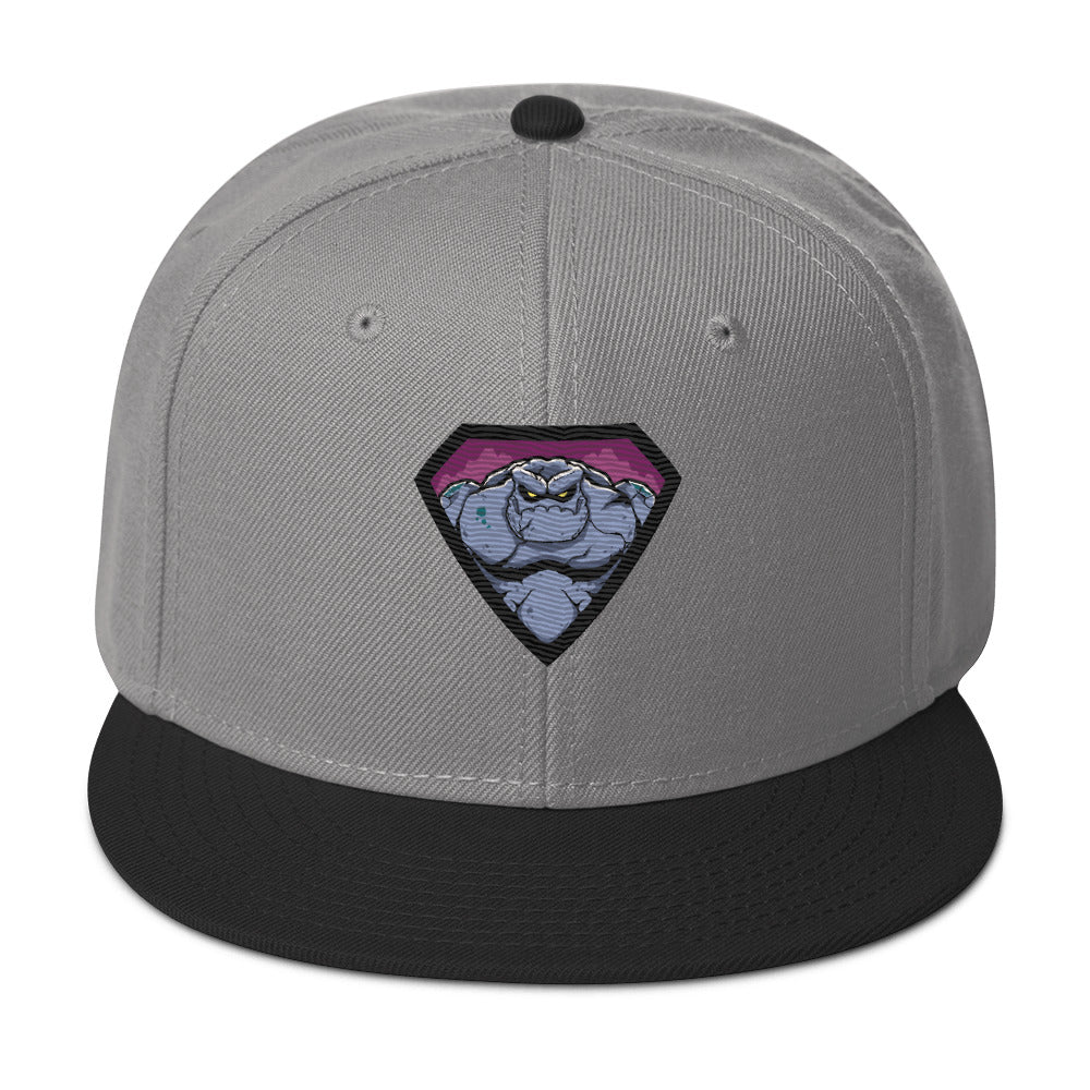 grau schwarze Snapback Cap mit einem farbigen, grimmig aussehenden Monster- oder Felsenwesen-Emblem auf der Vorderseite.