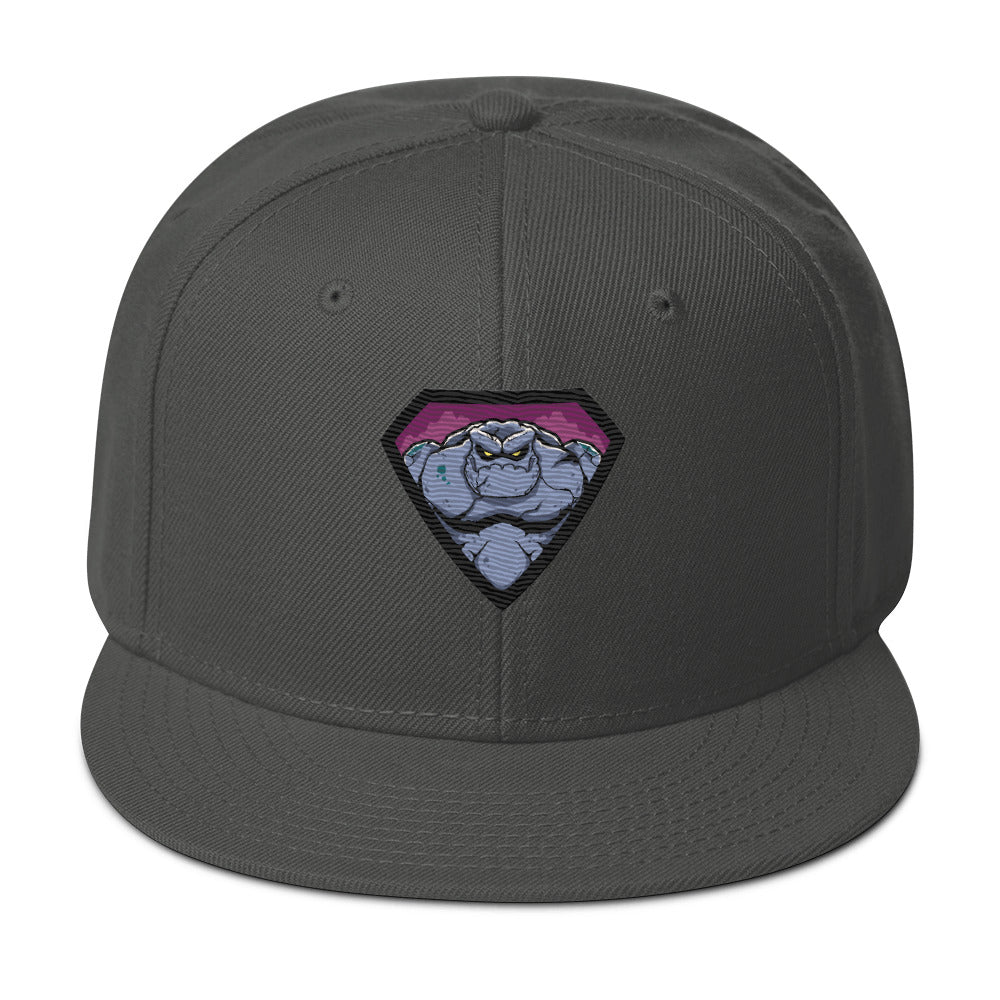 charcoal graue Snapback Cap mit einem farbigen, grimmig aussehenden Monster- oder Felsenwesen-Emblem auf der Vorderseite.