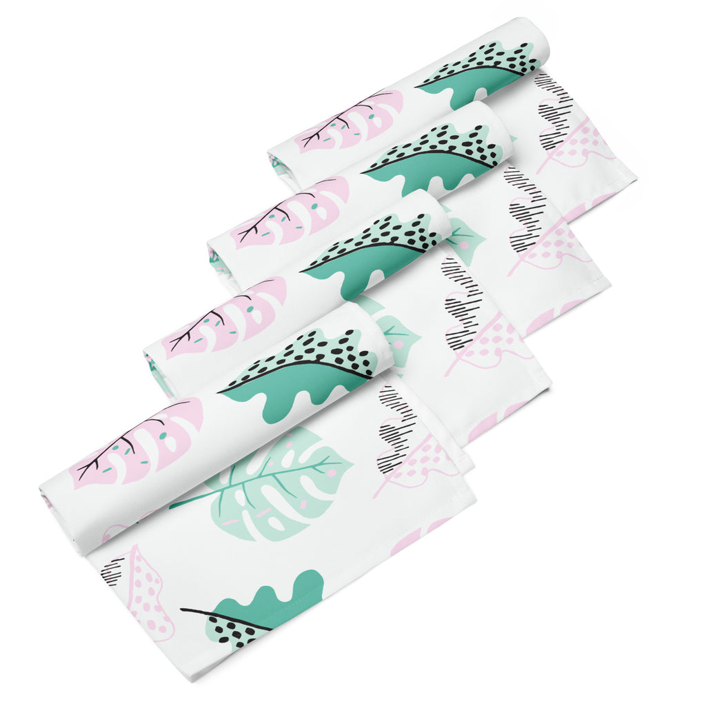 Ein Set aus vier gerollten Stoff-Servietten, freigestellt auf weißem Hintergrund. Der Hintergrund der Servietten ist weiß und zeigt ein modernes, abstraktes Muster aus Blättern in zarten Rosa- und Mintgrün-Tönen, ergänzt durch kleine schwarze Akzente.