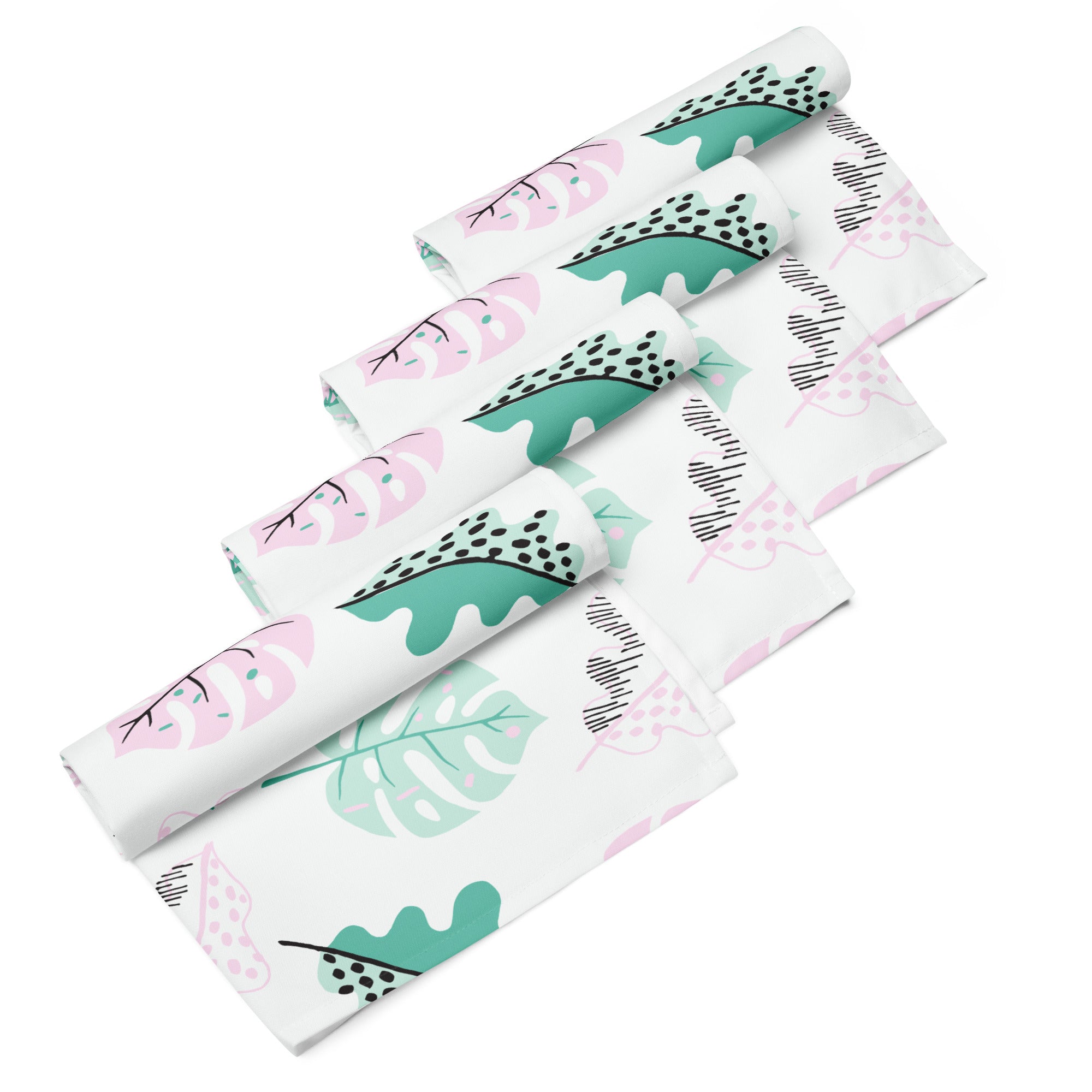 Ein Set aus vier gerollten Stoff-Servietten, freigestellt auf weißem Hintergrund. Der Hintergrund der Servietten ist weiß und zeigt ein modernes, abstraktes Muster aus Blättern in zarten Rosa- und Mintgrün-Tönen, ergänzt durch kleine schwarze Akzente.