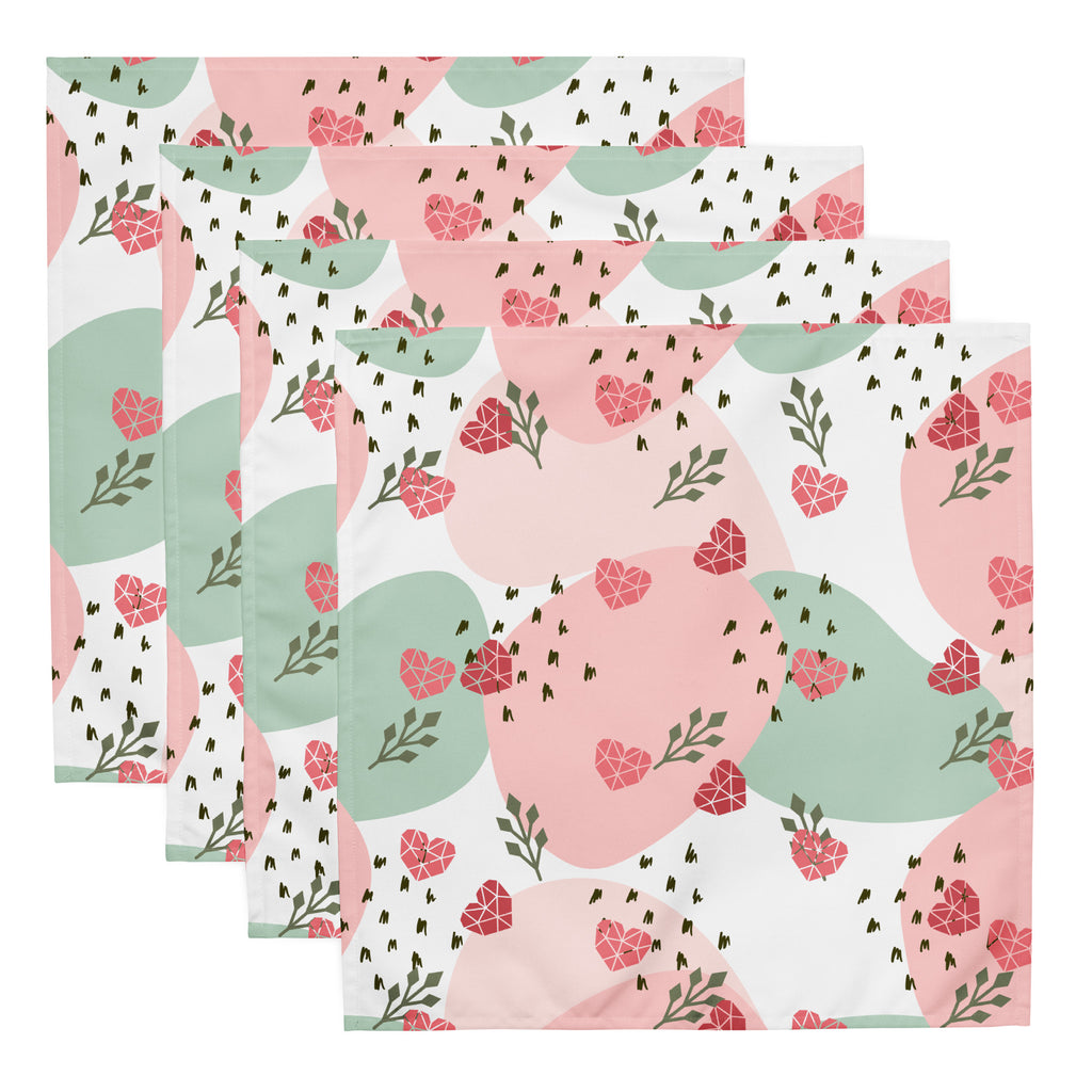Ein Set aus vier Stoff-Servietten, freigestellt auf weißem Hintergrund. Der Hintergrund ist weiß und zeigt ein abstraktes Muster mit rosafarbenen Herzen, hellgrünen Blattformen und kleinen schwarzen Strichen.