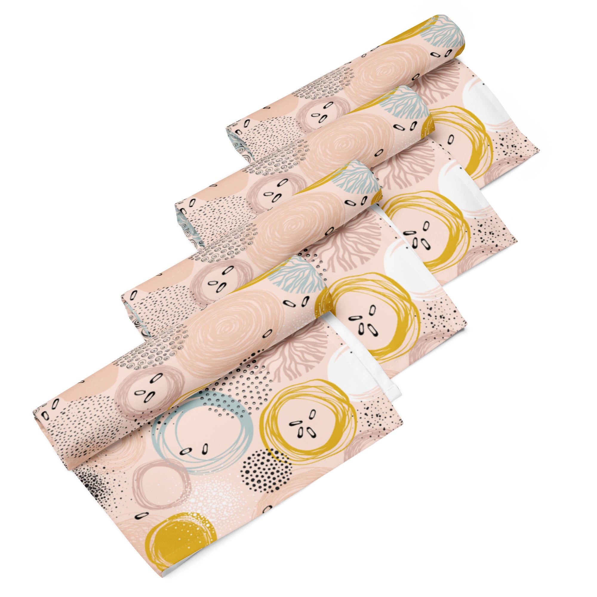 Ein Set aus vier gerollten Stoff-Servietten, freigestellt auf weißem Hintergrund. Die Servietten haben einen rosafarbenen Hintergrund und zeigen ein abstraktes Muster aus Kreisen in Gelb, Blau und Weiß sowie kleine schwarze Sprenkel.