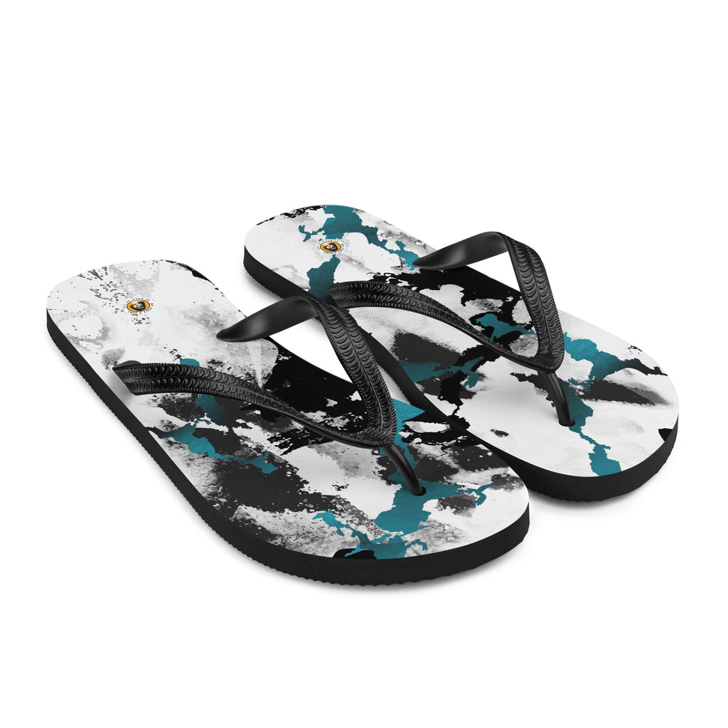 Ein Paar schwarze Herren-Flip-Flops mit einem Obermaterial, das ein abstraktes, dynamisches Muster aus unregelmäßigen schwarzen, weißen und türkisen Farbflächen oder Spritzern auf einem hellen Hintergrund zeigt. Die Riemen sind schwarz und haben eine strukturierte Oberfläche.