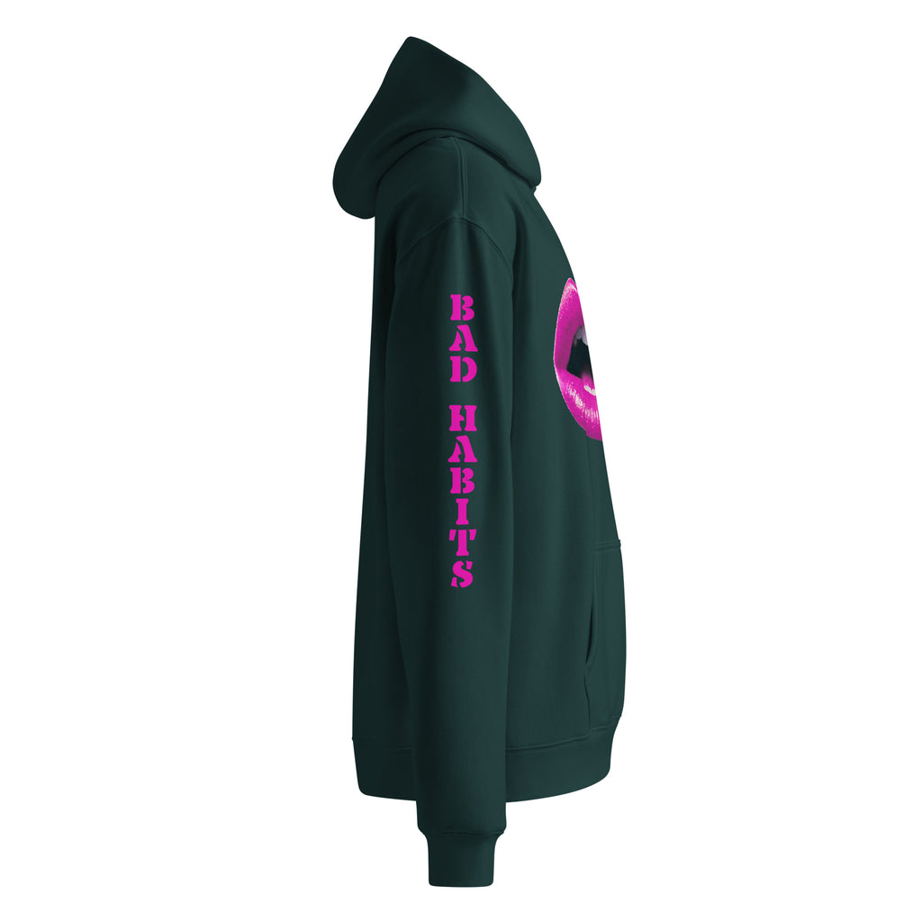Oversized Hoodie in piniengrün mit "Bad Habits" in pinken Design. Verfügt über ein Mund-Motiv auf der Vorderseite und einen "BAD HABITS" Schriftzug auf dem Ärmel. Erhältlich in 4 verschiedenen Farben.