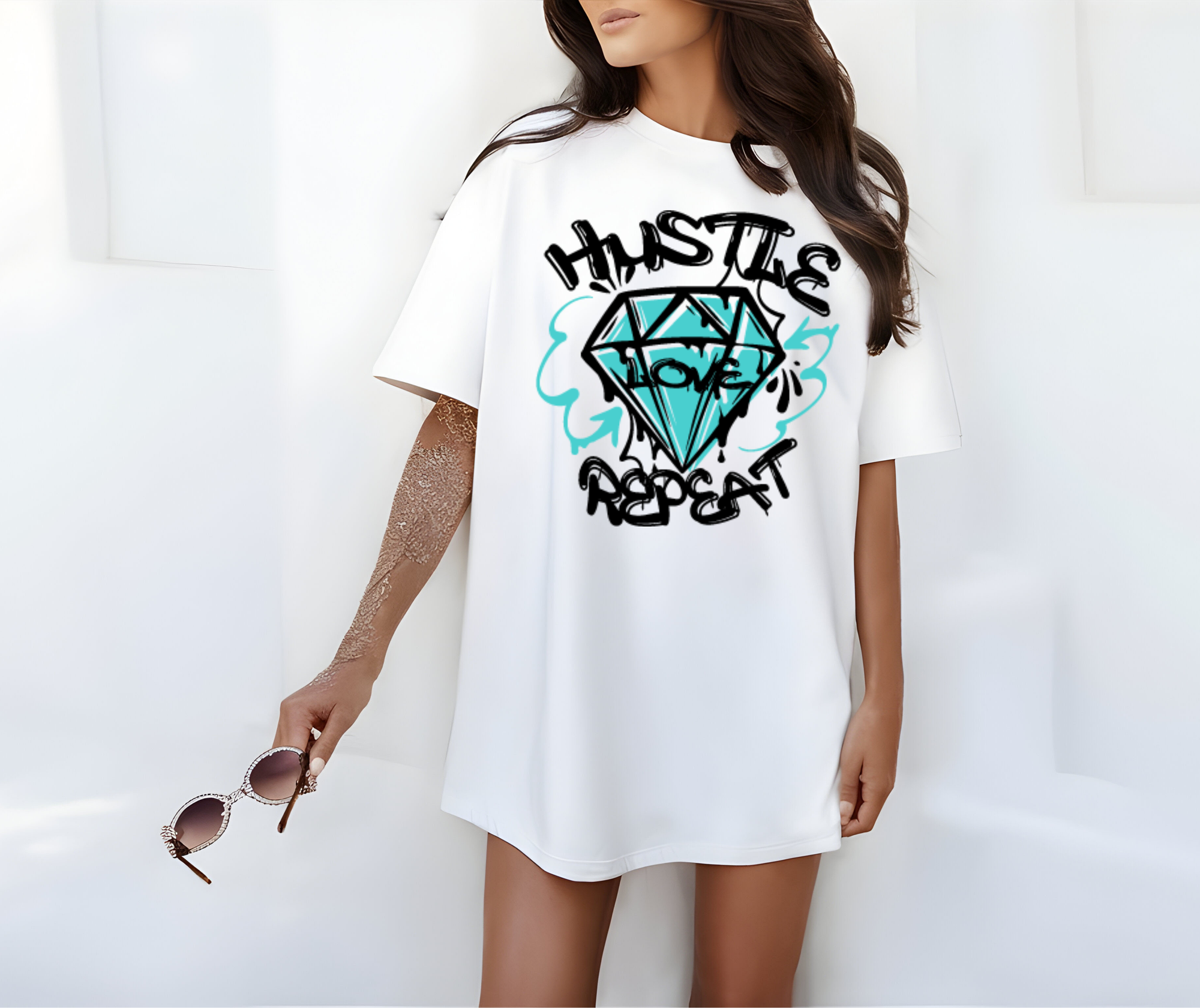 weibliches Mockup Model trägt ein weisses Oversized T-Shirt mit eine Grafiti Premium Druck großer schwarze schrift Hustle darunter einen Schwarzen Diamant in Outlines gefüllt mit grafiti Farbe in Mintgrün in der Mitte von dem Diamant steht schwarz Love und unter dem Diamant auch mit schwarzer Grafiti Druckschrift Repeat.