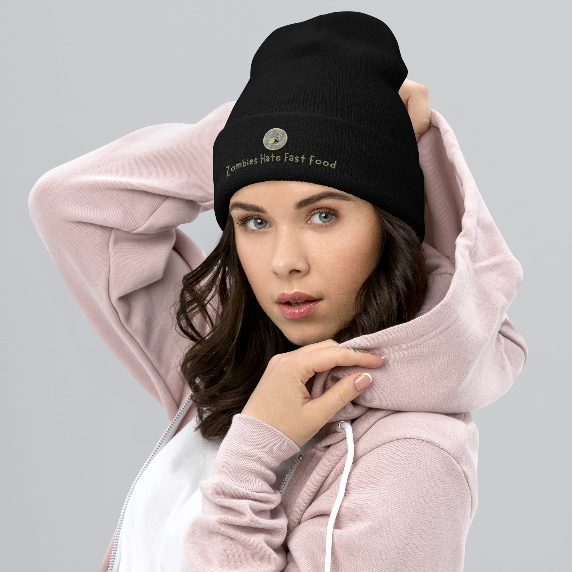 Ein weibliches Model trät ein schwarzes Cuffed Beanie mit aufgesticktem Patch von Homer und einem Donut mit einem grau-salbei farbenen Rahmen sowie einen Schriftzug darunter mit dem Satz "Zombies Hate Fast Food!" auf der Vorderseite. Designed, by Just a Girl.