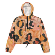 Ein Damen Cropped Windbreaker mit einem abstrakten Leopardenmuster in Orange-, Rosa- und Schwarztönen. Die Jacke hat eine Kapuze, einen halben Reißverschluss mit schwarzen Kordeln und einen verstellbaren Saum. By Just a Girl.
