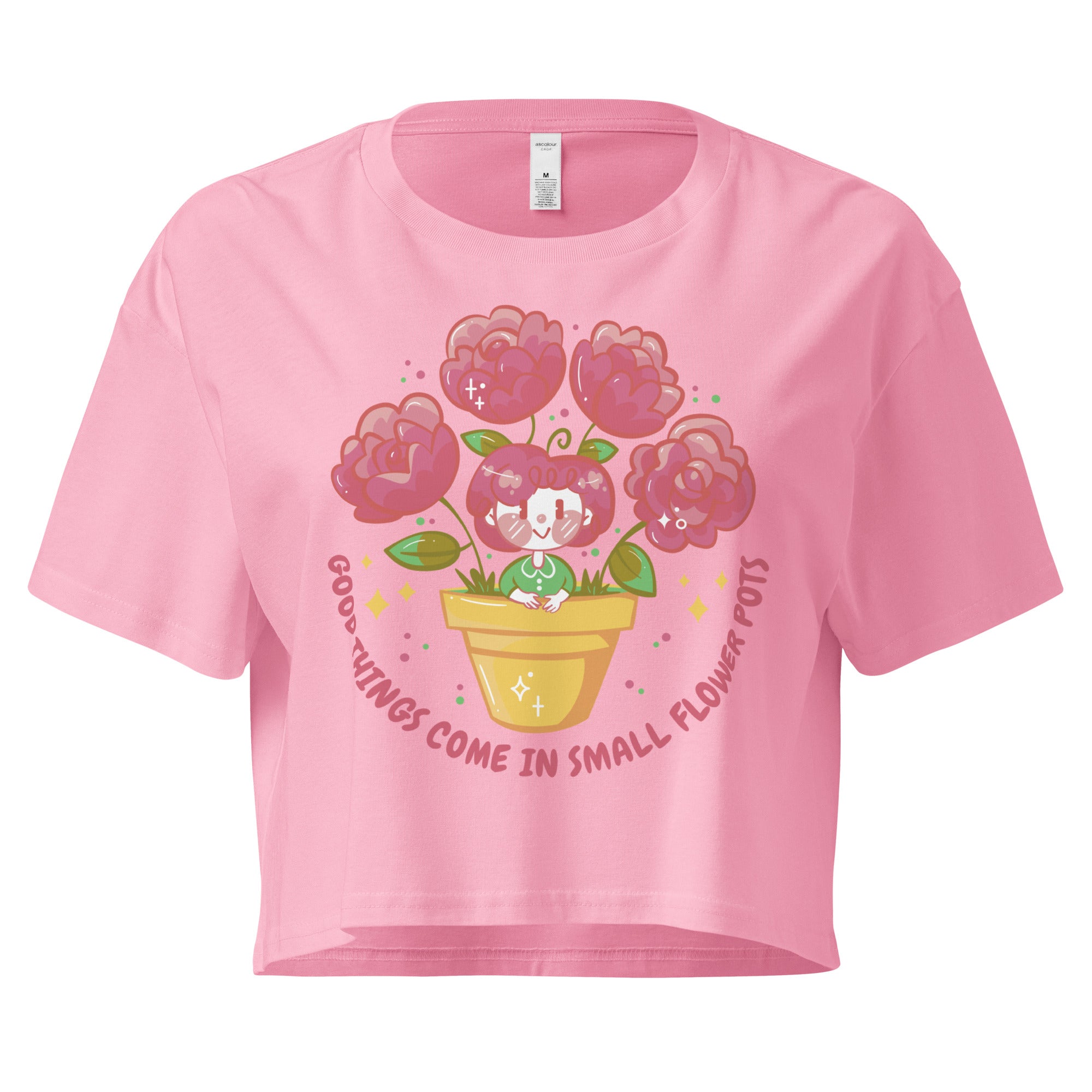 Ein bubblegum farbenes kurz geschnittenes Damen-T-Shirt (Crop Top) mit einer Illustration einer kleinen, lächelnden Figur in einem gelben Blumentopf. Um den Blumentopf herum sind mehrere große, rosa Blüten und grüne Blätter. Der Text "GOOD THINGS COME IN SMALL FLOWER POTS" ist in einem Bogen um das Motiv herum angeordnet, mit kleinen Sternen und Punkten.