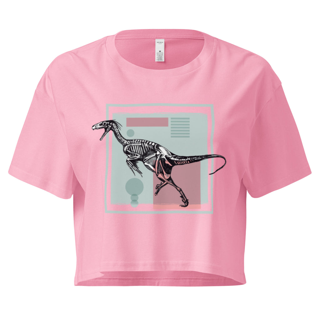 Ein bubblegum farbenes, kurz geschnittenes Damen-T-Shirt (Crop Top) mit einem weißen Kastenrahmen in der Mitte. Innerhalb des Rahmens befindet sich eine Illustration eines Dinosaurierskeletts, das auf einer Farbfeldfläche aus Rosa und Mintgrün platziert ist. Der Dinosaurier ist in einer Laufhaltung dargestellt.