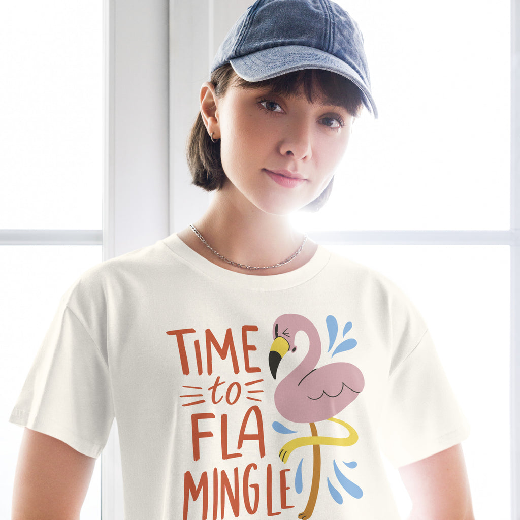 Ein  natur farbenes kurz geschnittenes Damen-T-Shirt (Crop Top) mit einer Illustration eines rosa Flamingos mit gelbem Bein und kleinen blauen Wasserspritzern. Daneben steht der Text "TIME TO FLA MINGLE" in einem verspielten, handgeschriebenen Stil in Orange und Rot.