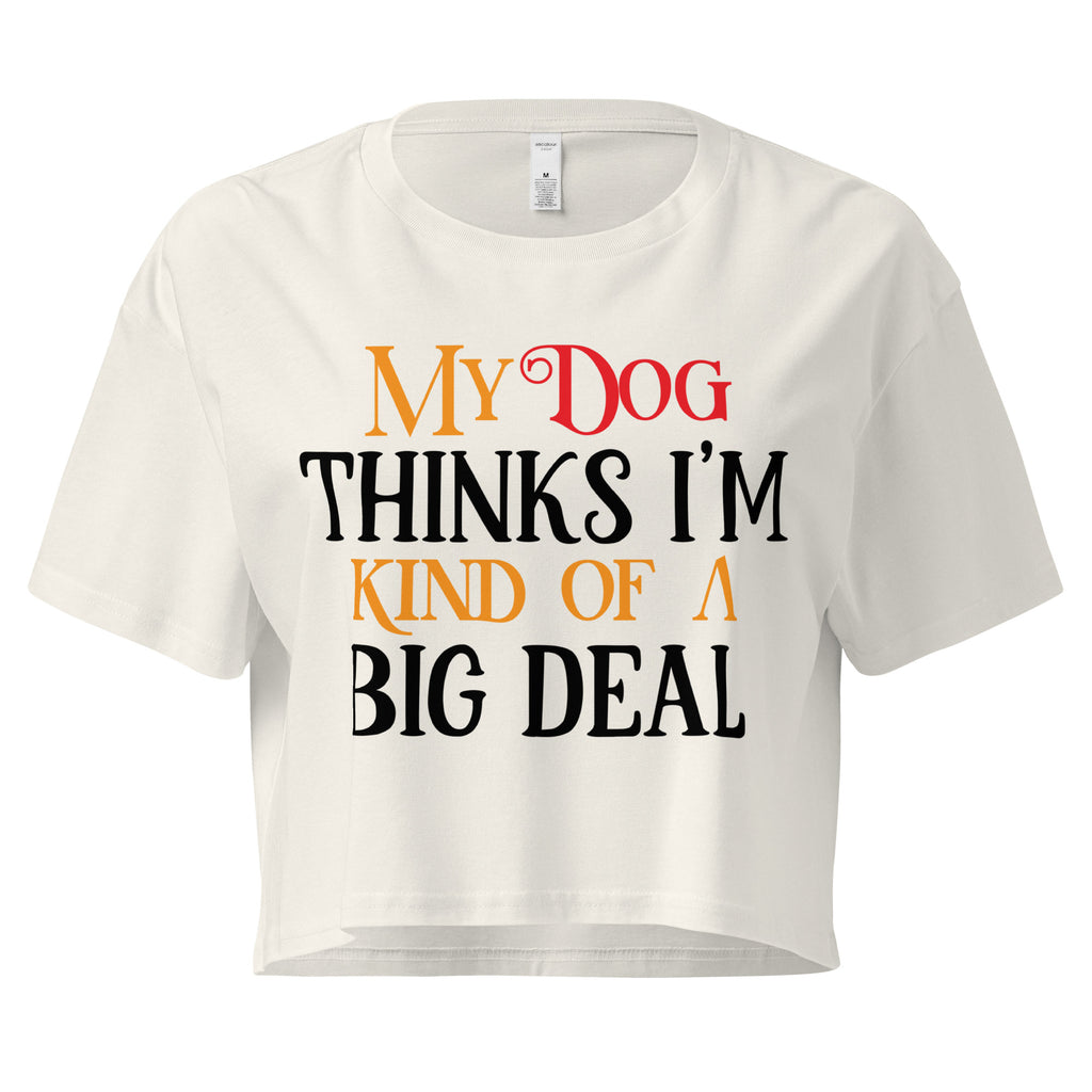 Ein ecrufarbenes, kurz geschnittenes Damen-T-Shirt (Crop Top) mit dem Text "My Dog THINKS I'M KIND OF A BIG DEAL". Die Wörter "Dog" und "A" sind in Rot, "KIND OF" und "BIG" in Orange, und der restliche Text in Schwarz gehalten.