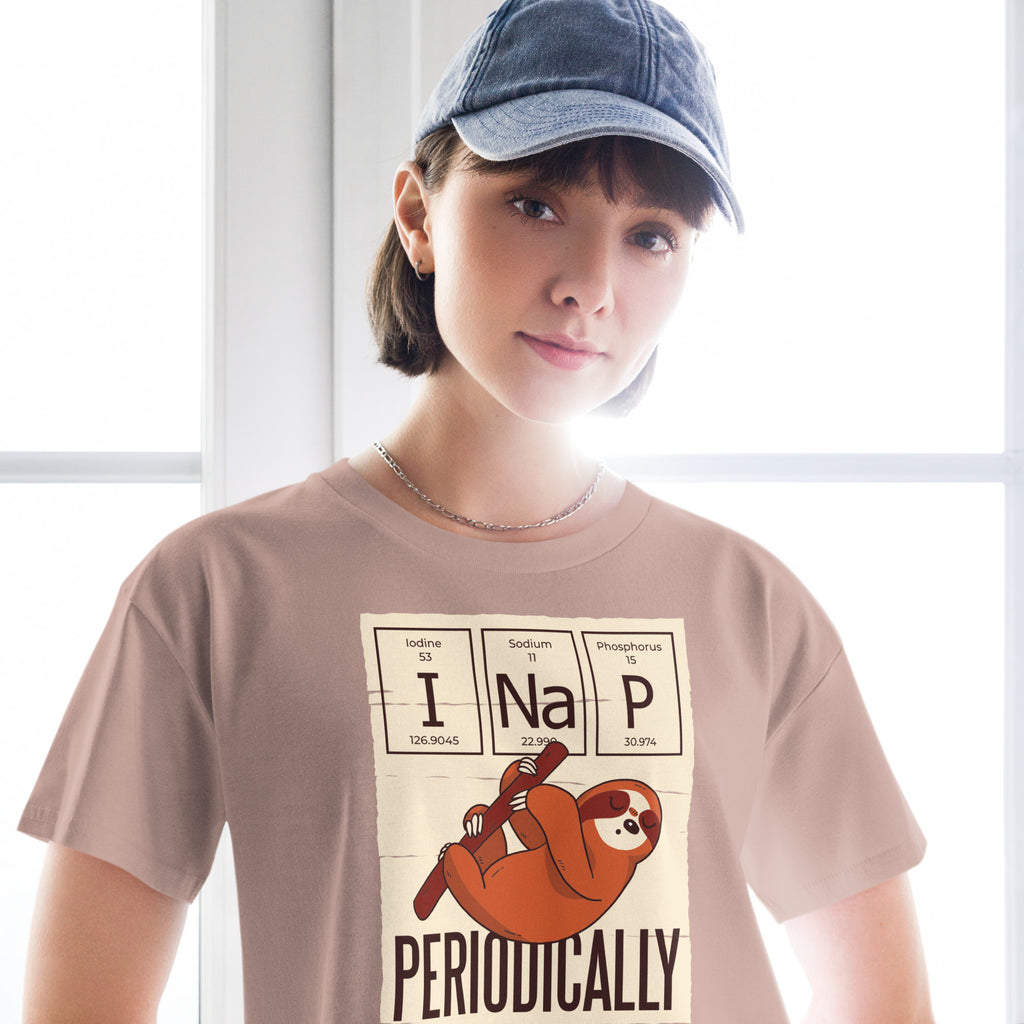 Ein hazy-pink farbenes kurz geschnittenes Damen-T-Shirt (Crop Top) mit einer Illustration eines Faultiers, das an einem Ast hängt. Darüber befinden sich drei Felder im Stil des Periodensystems der Elemente mit den Symbolen "I" (Iodine), "Na" (Sodium) und "P" (Phosphorus), die zusammen "I Na P" bilden. Unter dem Faultier steht das Wort "PERIODICALLY". Der Hintergrund des Motivs ist hellbeige.
