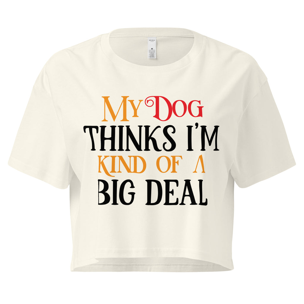 Ein naturfarbenes, kurz geschnittenes Damen-T-Shirt (Crop Top) mit dem Text "My Dog THINKS I'M KIND OF A BIG DEAL". Die Wörter "Dog" und "A" sind in Rot, "KIND OF" und "BIG" in Orange, und der restliche Text in Schwarz gehalten.