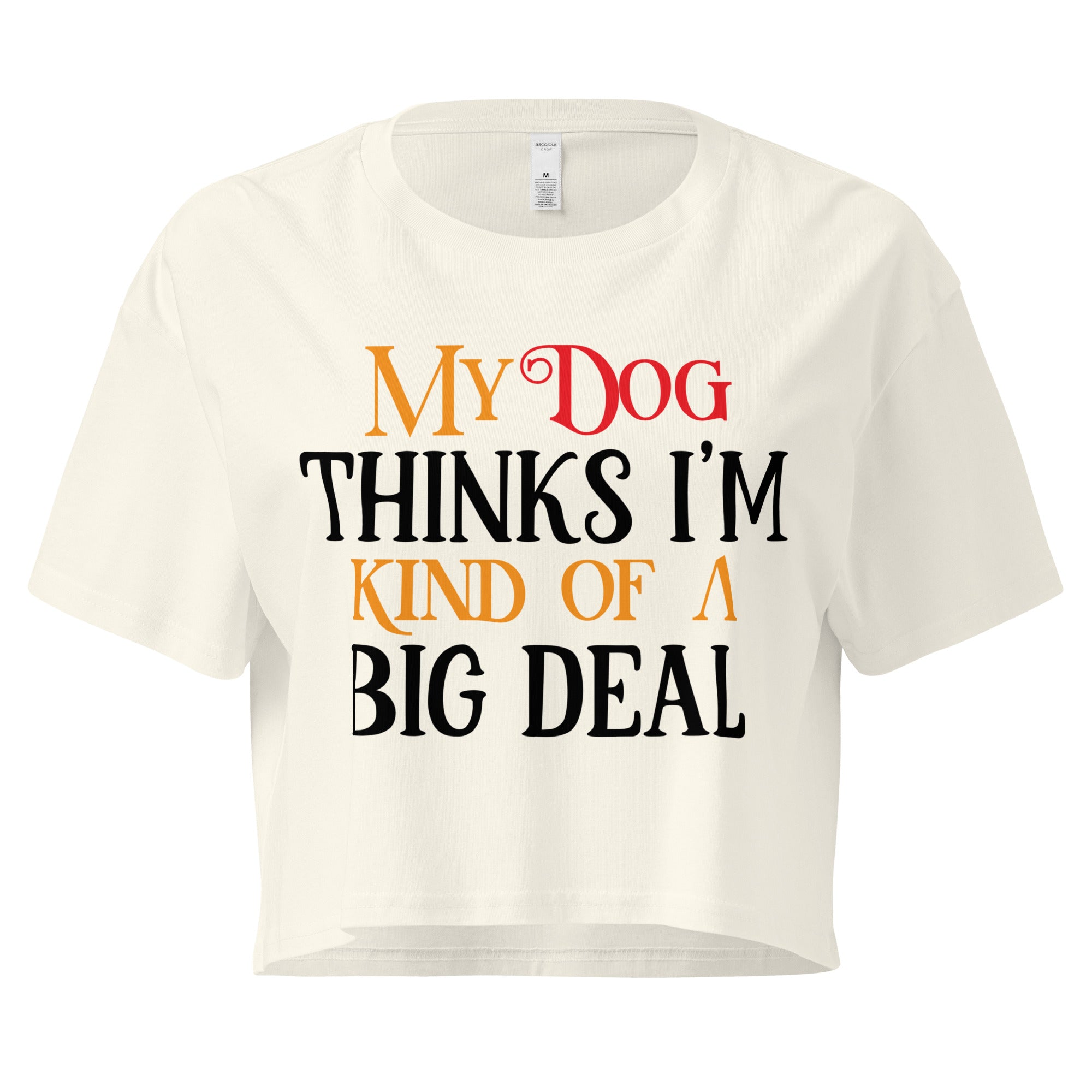 Ein naturfarbenes, kurz geschnittenes Damen-T-Shirt (Crop Top) mit dem Text "My Dog THINKS I'M KIND OF A BIG DEAL". Die Wörter "Dog" und "A" sind in Rot, "KIND OF" und "BIG" in Orange, und der restliche Text in Schwarz gehalten.