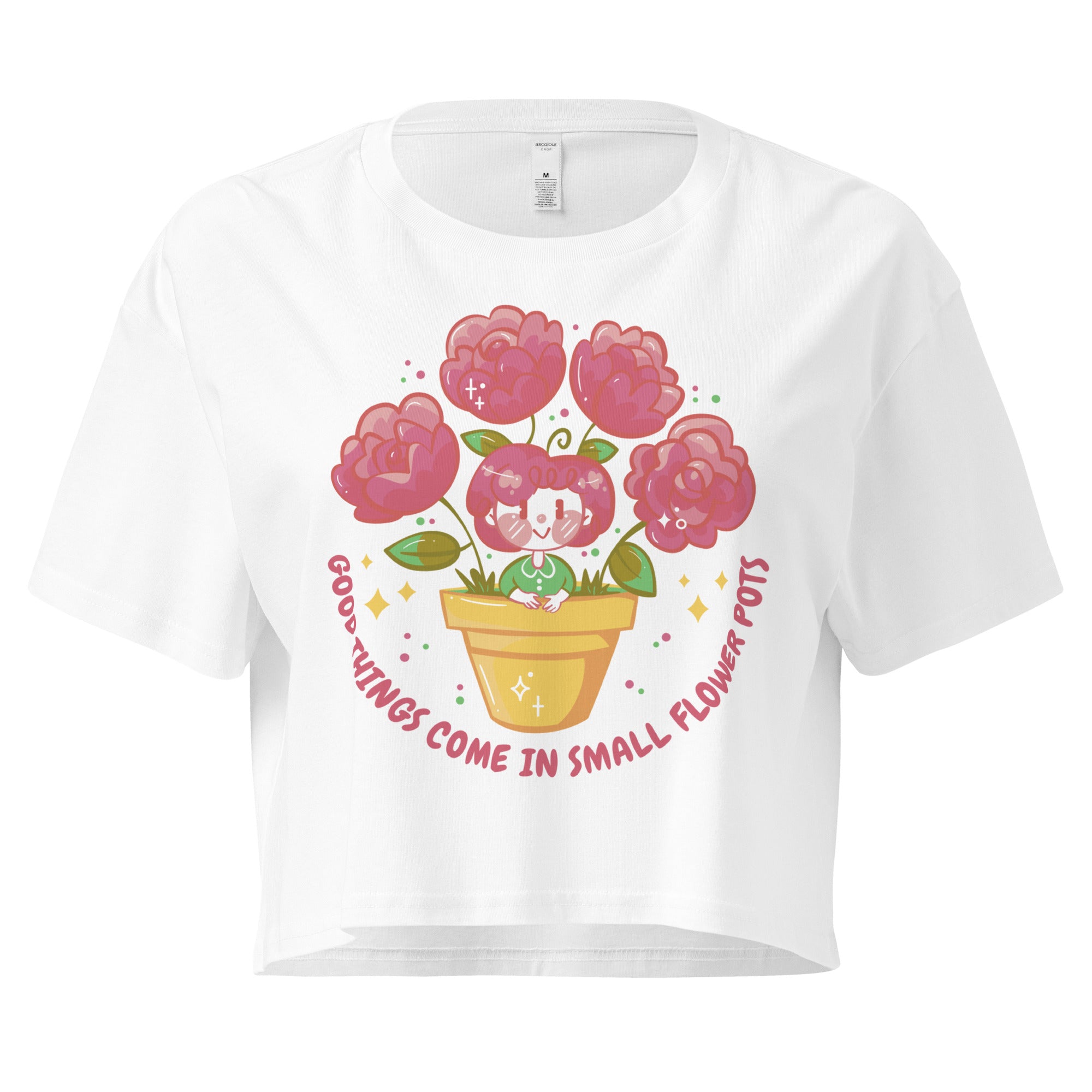 Ein weißes kurz geschnittenes Damen-T-Shirt (Crop Top) mit einer Illustration einer kleinen, lächelnden Figur in einem gelben Blumentopf. Um den Blumentopf herum sind mehrere große, rosa Blüten und grüne Blätter. Der Text "GOOD THINGS COME IN SMALL FLOWER POTS" ist in einem Bogen um das Motiv herum angeordnet, mit kleinen Sternen und Punkten.