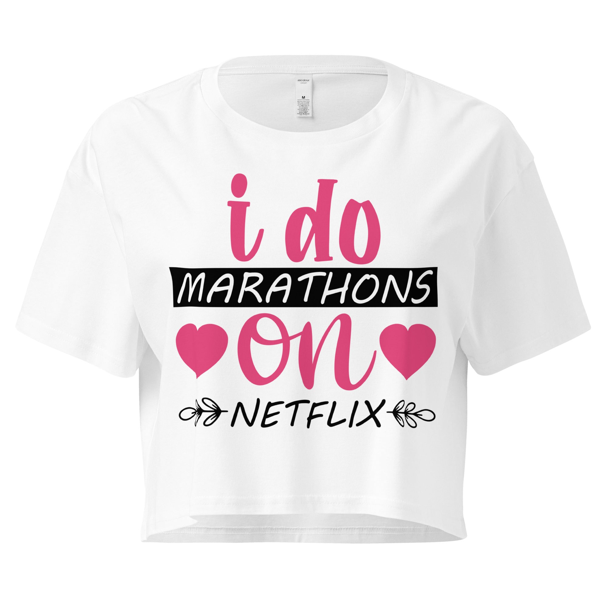 Ein weißes, kurz geschnittenes Damen-T-Shirt (Crop Top) mit dem Text "i do MARATHONS on NETFLIX" auf der Vorderseite. Der Text "i do" und "on" ist in Pink, "MARATHONS" in Schwarz auf einem schwarzen Balken, und "NETFLIX" ebenfalls in Schwarz, umgeben von kleinen schwarzen Herzen und floralen Ranken.