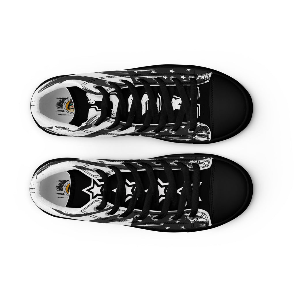 Ein Paar High-Top Canvas Schuhe in Schwarz mit Ansicht von oben geschlossen mit einem Schwarz-Weiß-Design, das an die USA-Flagge erinnert. Beide Schuhe haben eine schwarze Schuhzunge; die linke trägt den weißen College-Schriftzug "USA" und die rechte vier weiße doppelten Sterne. Die Schuhsohle, Fusskappe und Schnürsenkel sind schwarz. Designed, by Just a Girl.
