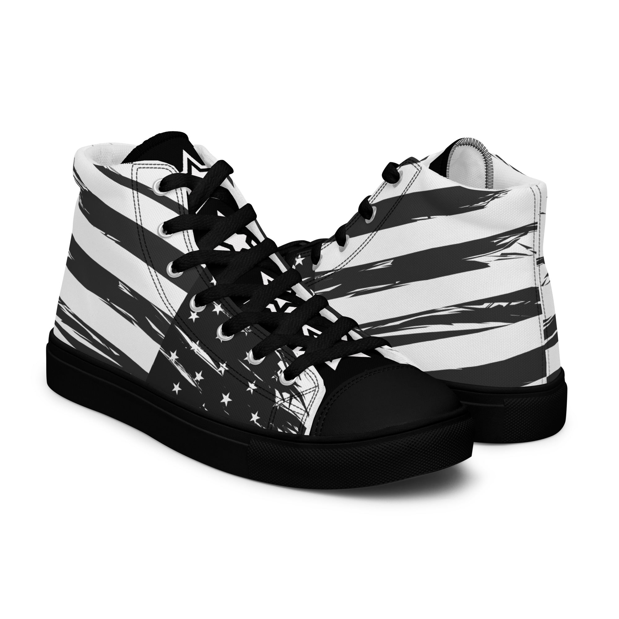 Ein Paar gegensätzliche Anzeigende High-Top Canvas Schuhe in Schwarz mit einem Schwarz-Weiß-Design, das an die USA-Flagge erinnert. Beide Schuhe haben eine schwarze Schuhzunge; die linke trägt den weißen College-Schriftzug "USA" und die rechte vier weiße doppelten Sterne. Die Schuhsohle, Fusskappe und Schnürsenkel sind schwarz. Designed, by Just a Girl.