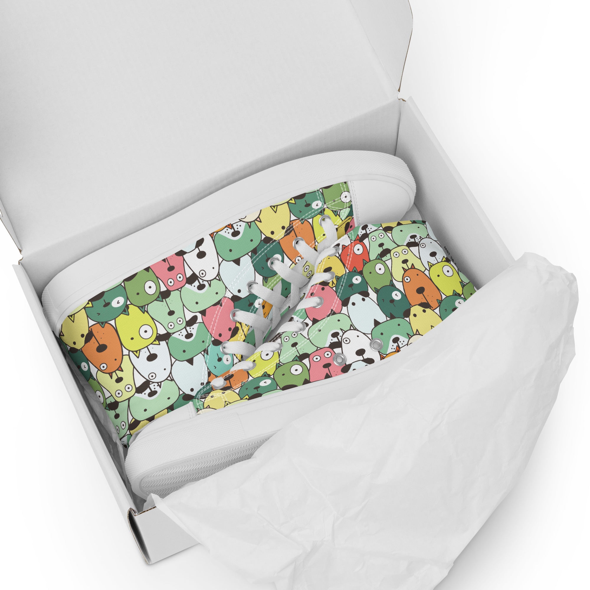 Ansicht liegend im Schuhkarton der weißen High-Top-Sneaker mit einem dichten, sich wiederholenden Muster aus stilisierten, farbenfrohen Cartoon-Köpfen von Tieren oder fantastischen Kreaturen in Tönen wie Gelb, Grün, Rosa, Orange und Hellblau. Die Schnürsenkel und Zehenkappen sind weiß. Designed, by Just a Girl.
