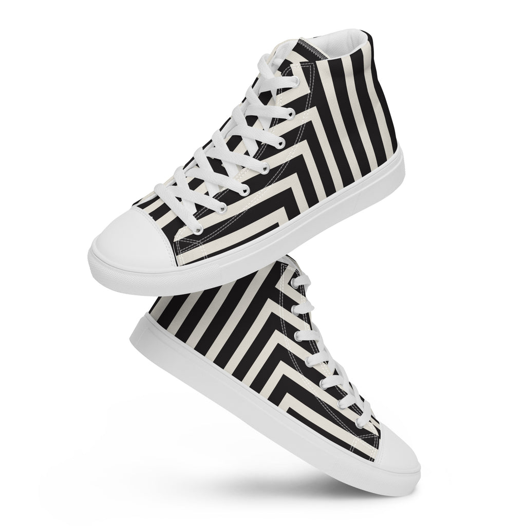 Ein Paar schwebende weiße High-Top-Sneaker mit einem grafischen Muster aus diagonal verlaufenden, breiten schwarzen und weißen Streifen, die an der Seite einen Chevron-Effekt (Zickzack) bilden. Die Schnürsenkel und Zehenkappen sind weiß. Designed, by Just a Girl.