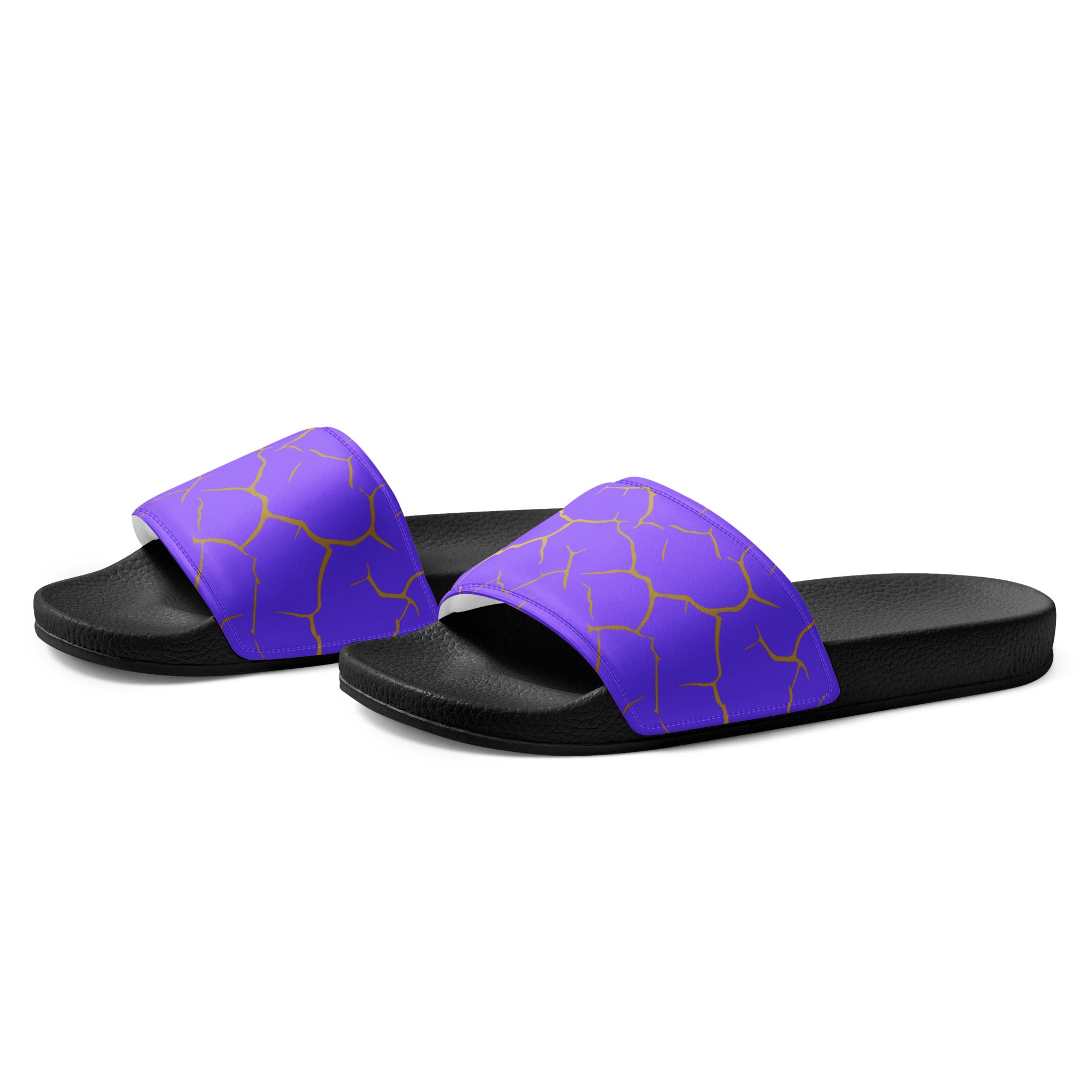 Ein Paar schwarze Flip-Flops mit einem Obermaterial in einem kräftigen Violett, das von einem unregelmäßigen Muster aus gebrochenen goldenen Linien durchzogen ist, die wie Risse oder Sprünge aussehen. Die Riemen sind schwarz und haben eine strukturierte Oberfläche. Auf der Ferse jedes Flip-Flops befindet sich ein rundes gelbes Emblem mit dem Text "BY JUST A GIRL" und "BE BOLD. BE YOU" sowie dem stilisierten Kopf einer Frau mit Bob-Frisur und Sonnenbrille.