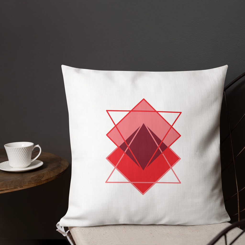 Ein Dekokissen der Grundton ist cremeweiß ist mit einem minimalistischen abstrakten Motiv aus überlappenden, roten und rosafarbenen geometrischen formen in der Größe 18"x18".